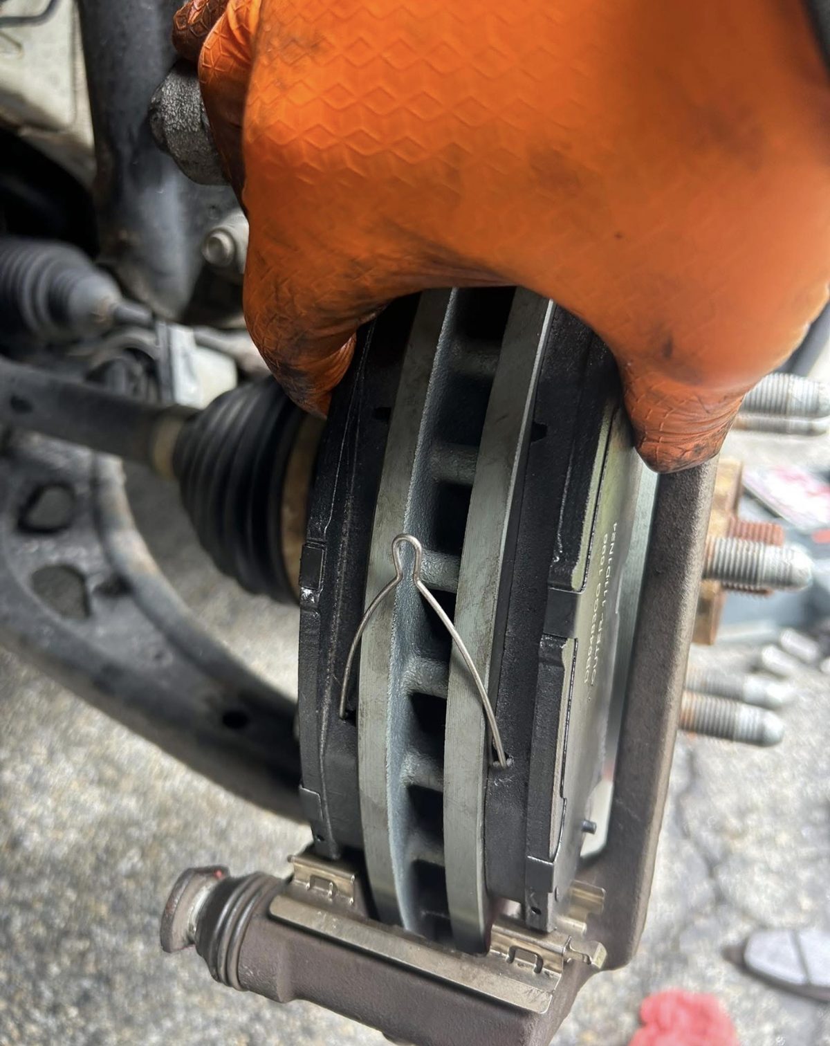 Technician fitting new brake pads into the caliper bracket during an on-site brake job