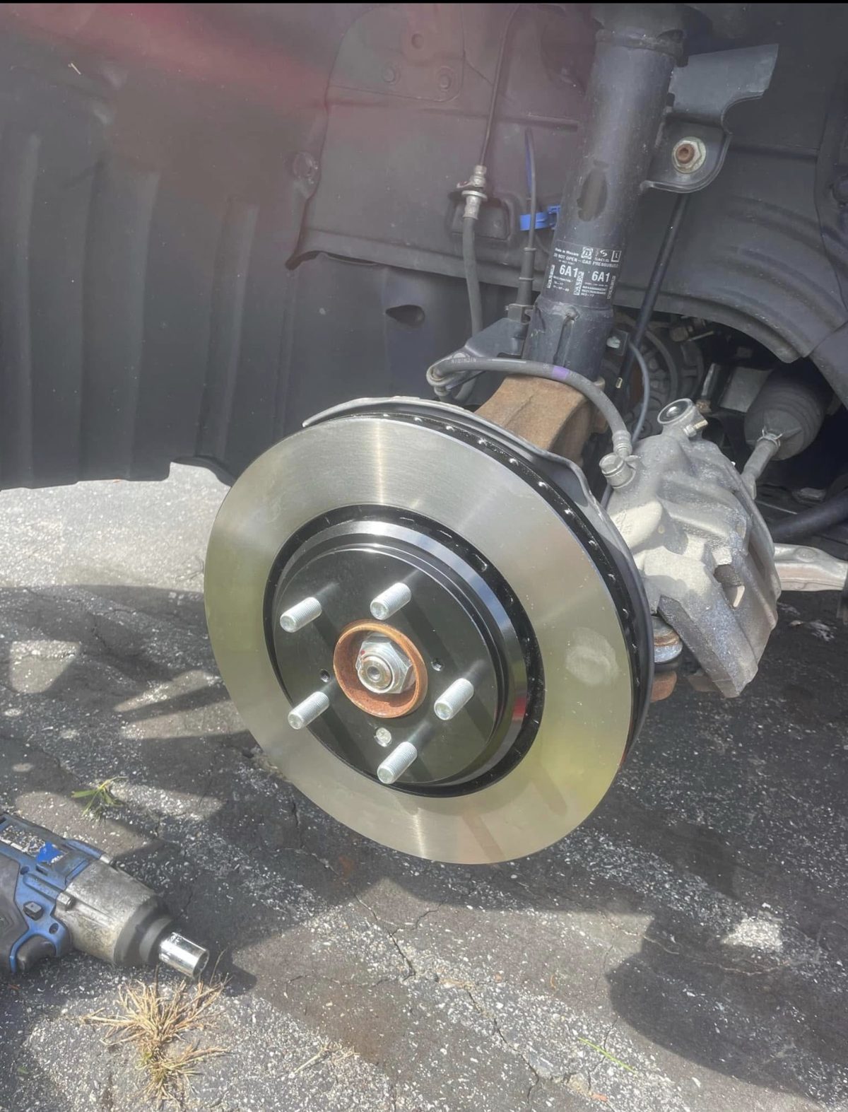 Brand-new coated brake rotor installed on a customer's car during a mobile brake replacement